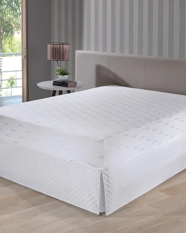 Cama de casal arrumada com roupa de cama branca num quarto claro